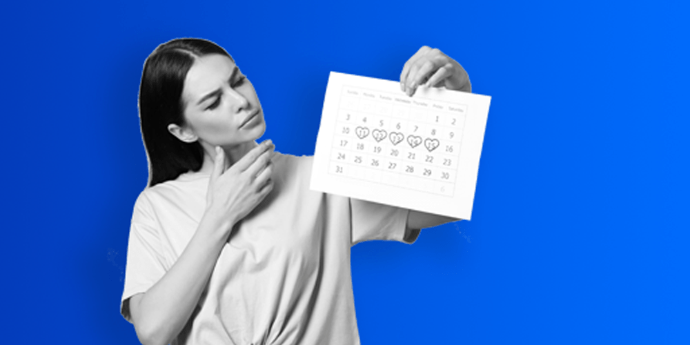 A woman holding up a monthly calendar with certain dates circled and looking at them.