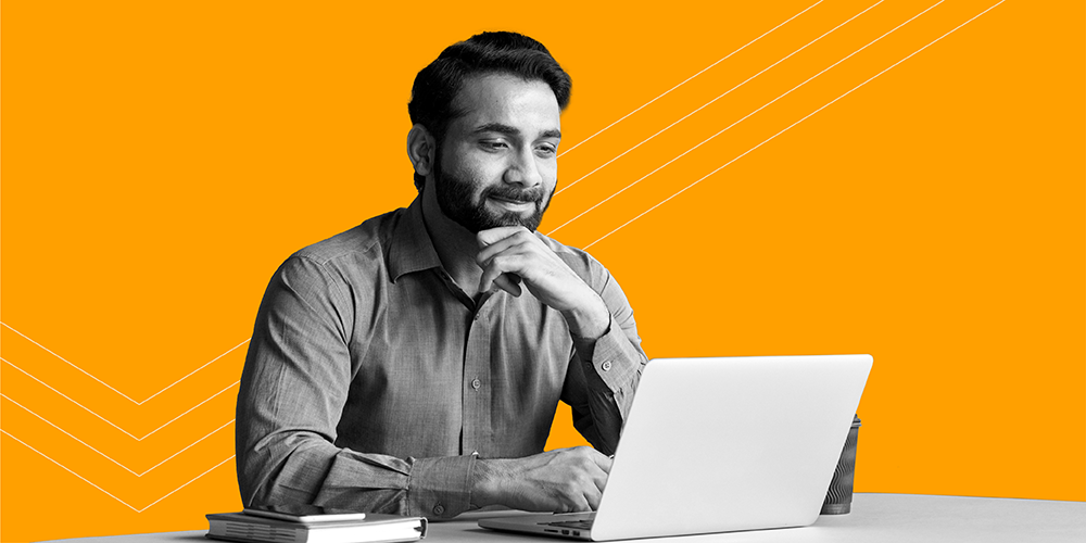 man with beard smiling while working on his laptop