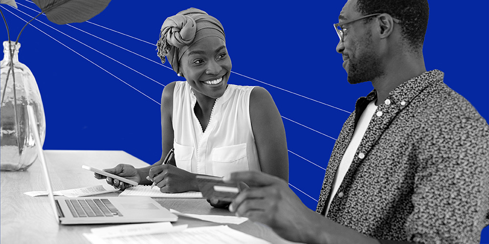 woman holding calculator and pen working at desk with man holding a credit card